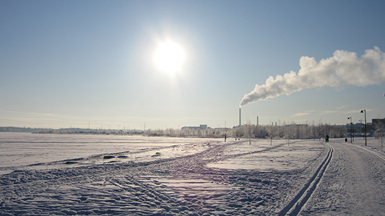 Talvikuva, jossa etualalla hiihtoladut ja takana näkyy lämpövoimalan tupruttava piippu.
